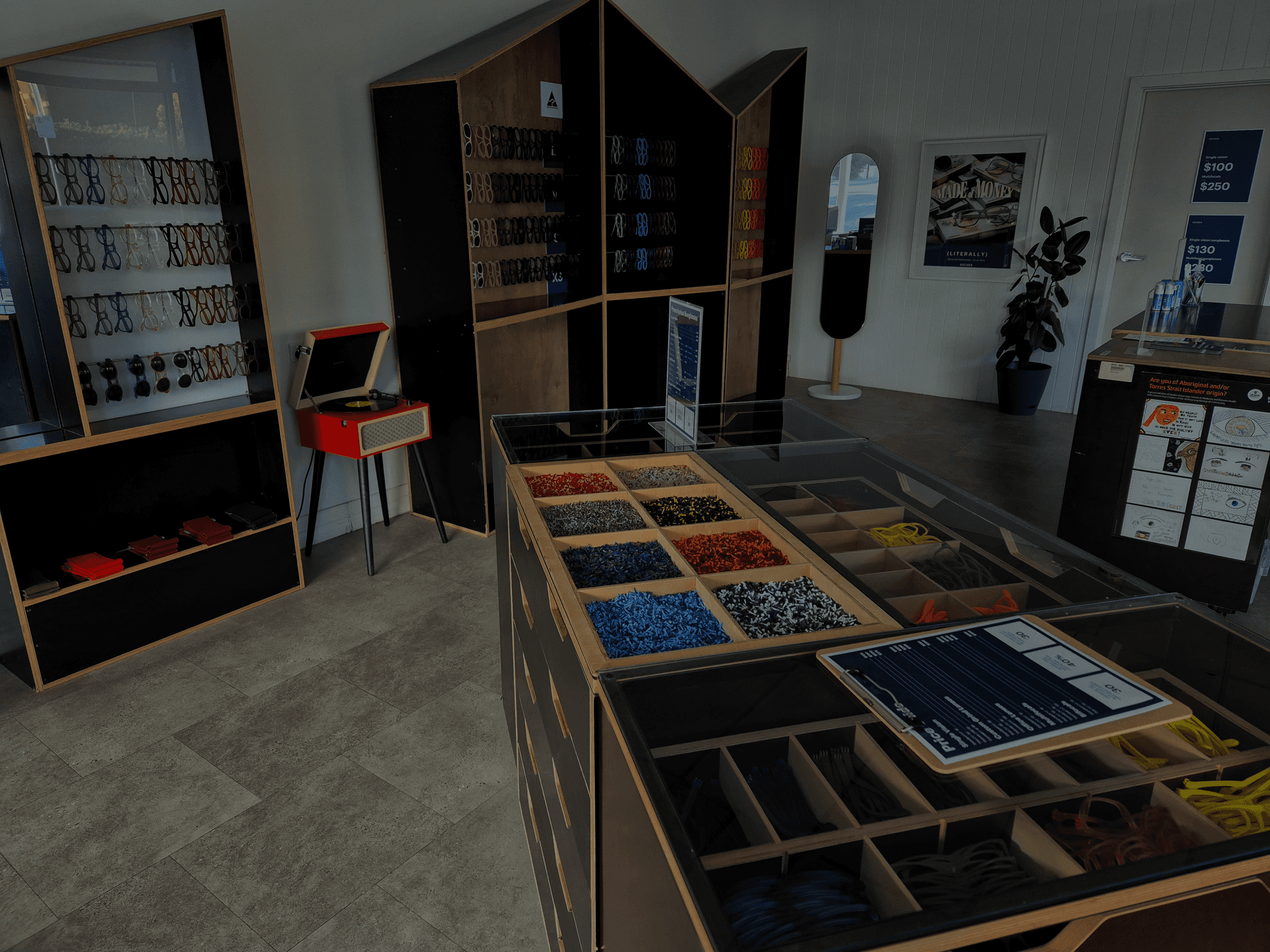 Modern interior of Dresden Vision Geelong featuring minimalist plywood and black displays filled with colorful eyewear frames and accessories.